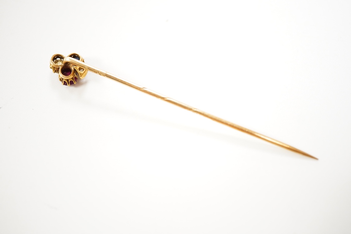 An early 20th century Viennese yellow metal, ruby, diamond and sapphire set 'clover' stick pin, 68mm, together with a yellow metal and blue enamel set stick pin.
